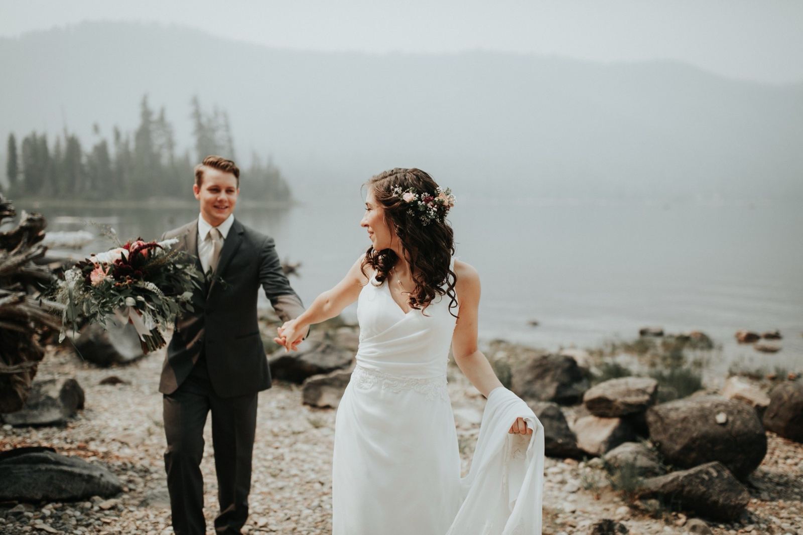 A couple walking hand in hand along a misty lake shore
